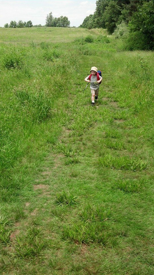 A young boy running through a grassy field.