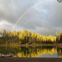 A rainbow over a lake with a boat in the background.