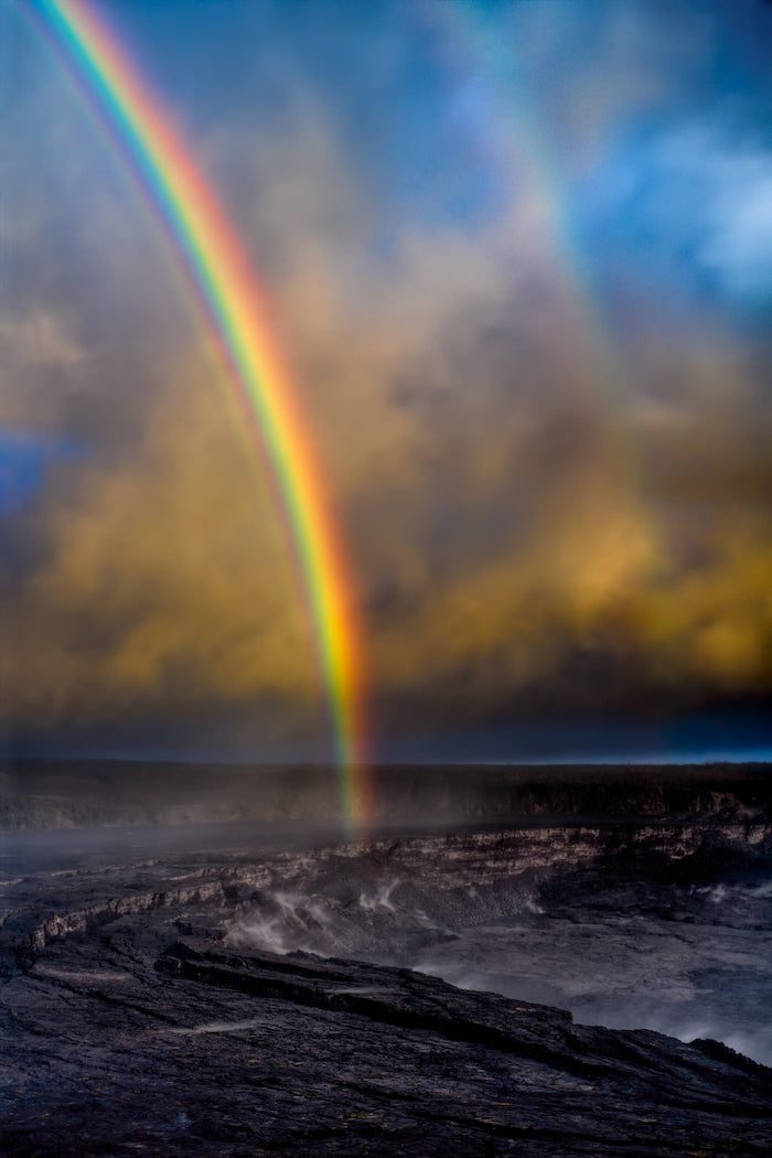 A rainbow is seen over a lava field.