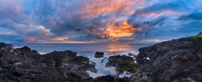 A sunset over a rocky cliff and ocean.