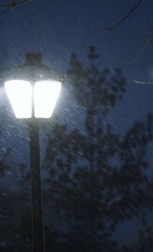 A street light is lit up in the snow.