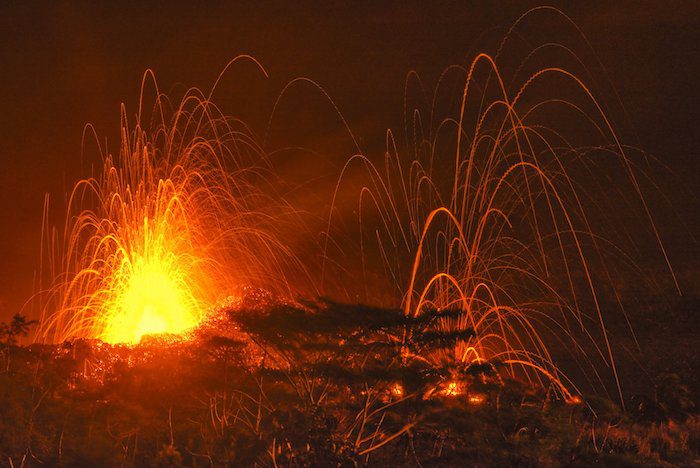 Lava spewing out of a volcano at night.