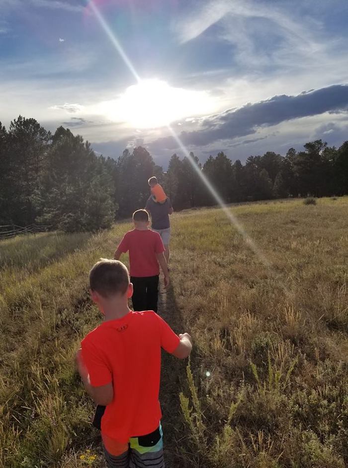 A group of boys running through a grassy field.