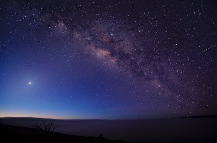 The milky way over a mountain in the night sky.