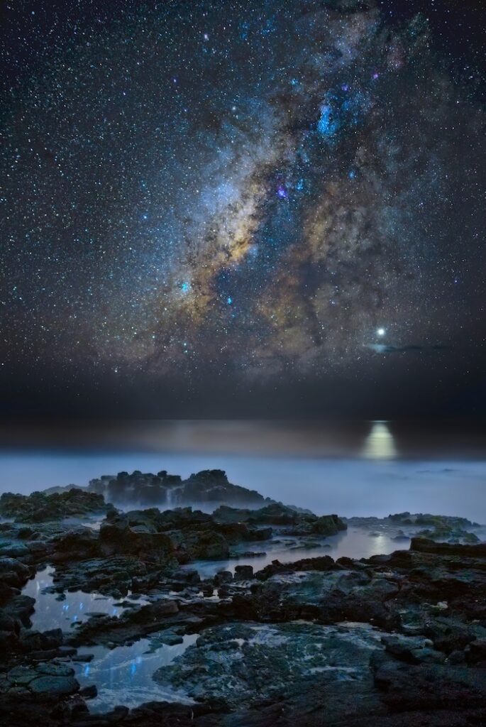 The milky in the sky above a rocky beach.