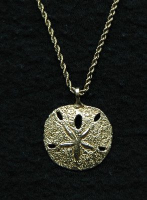 A gold sand dollar necklace on a black background.