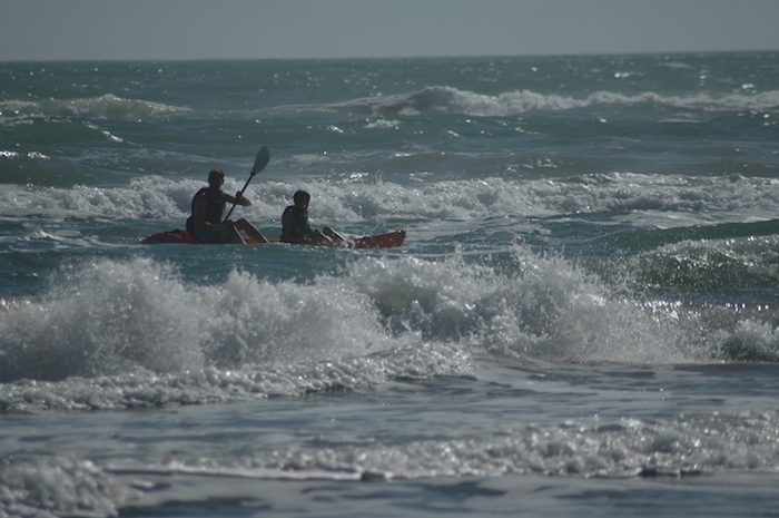 Two people in a canoe in the ocean.