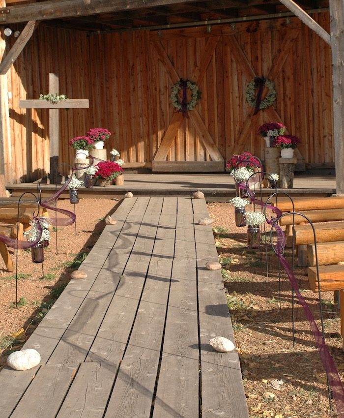 A wooden walkway with a wooden bench and flowers.