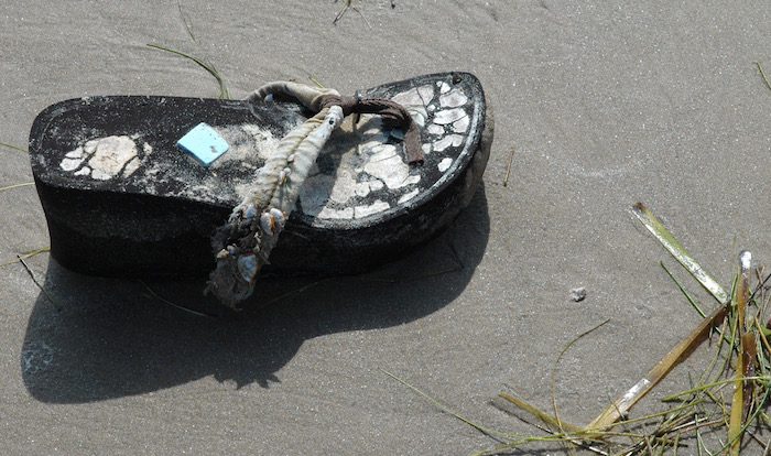 A pair of flip flops laying on the sand.