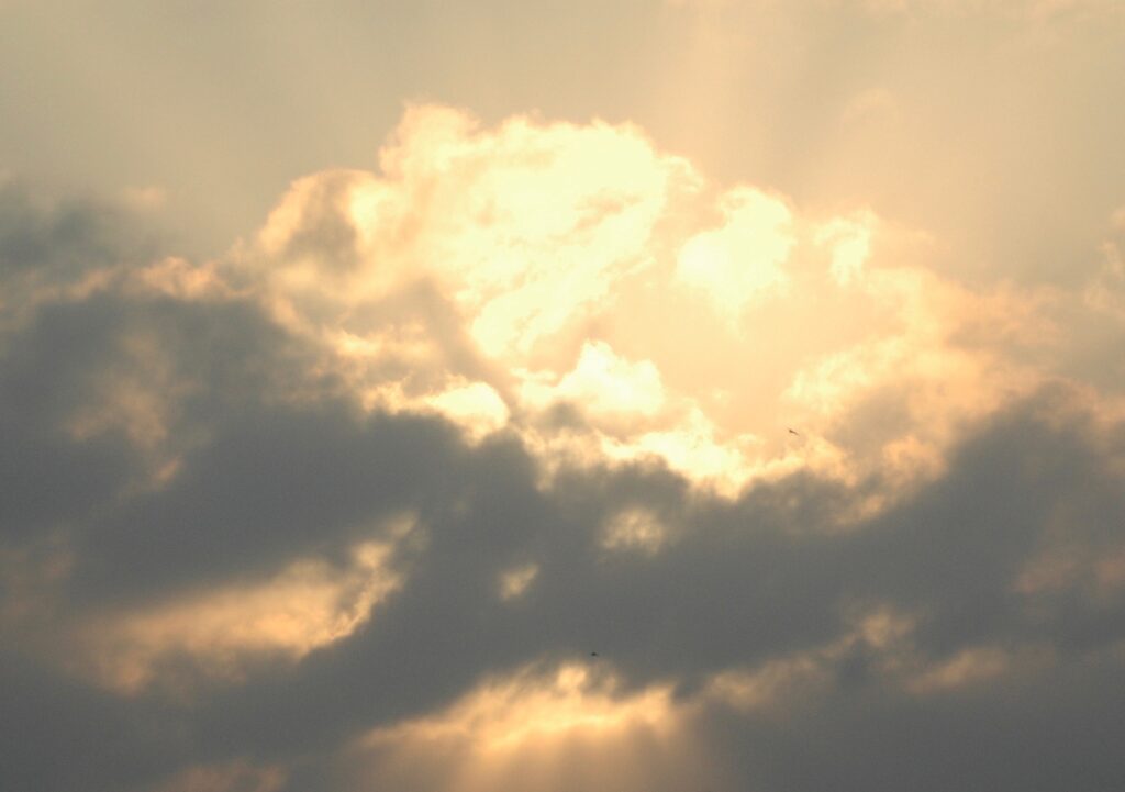 The sun is shining through a cloudy sky.