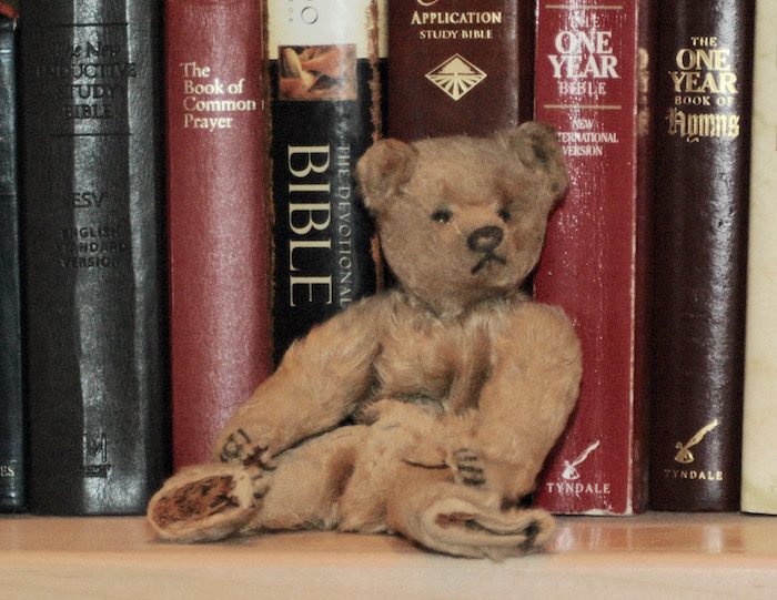 A teddy bear sitting in front of books.