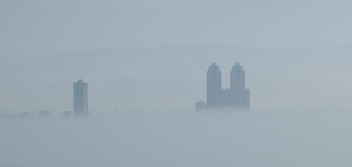 The skyline of kuala lumpur, malaysia is covered in fog.