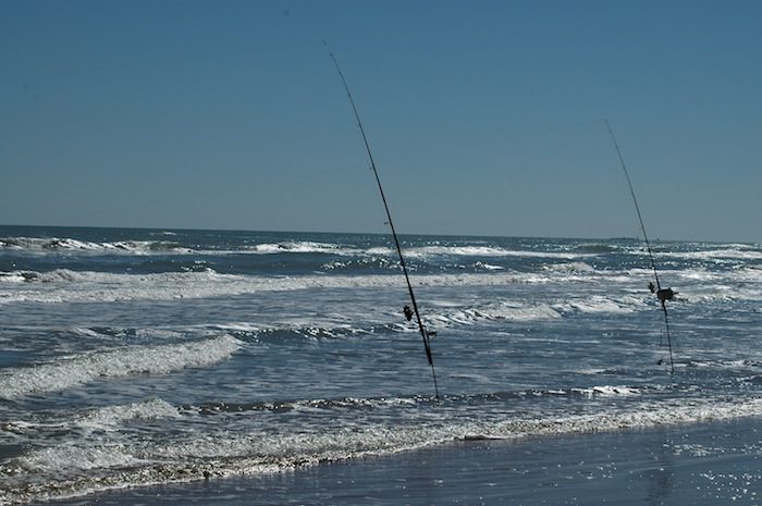 Two fishing poles on the beach.