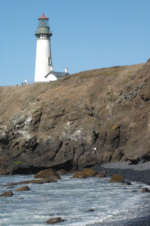 A lighthouse sits on top of a rocky cliff.