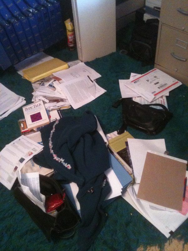 A messy office with a lot of papers on the floor.