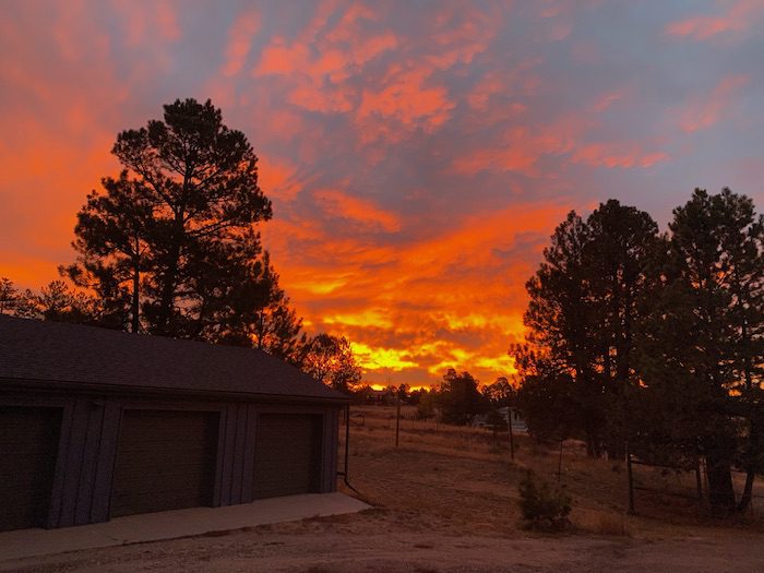 A sunset over a garage with trees in the background.