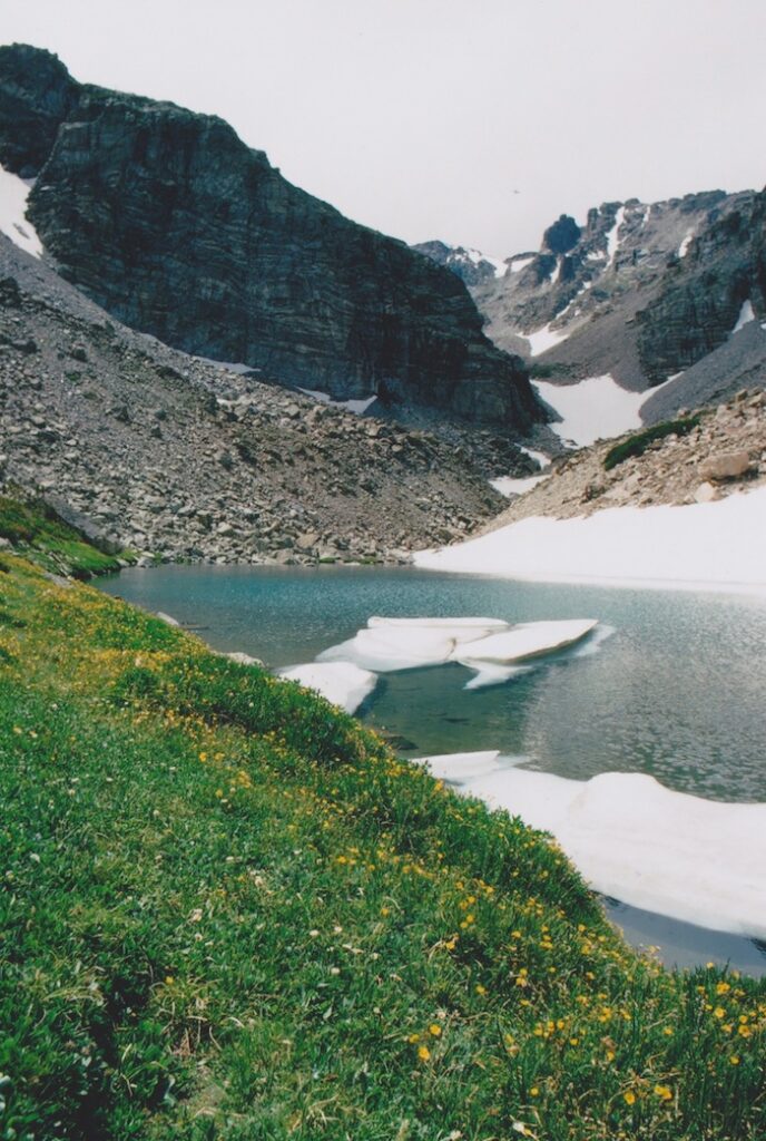 A lake surrounded by mountains and green grass.