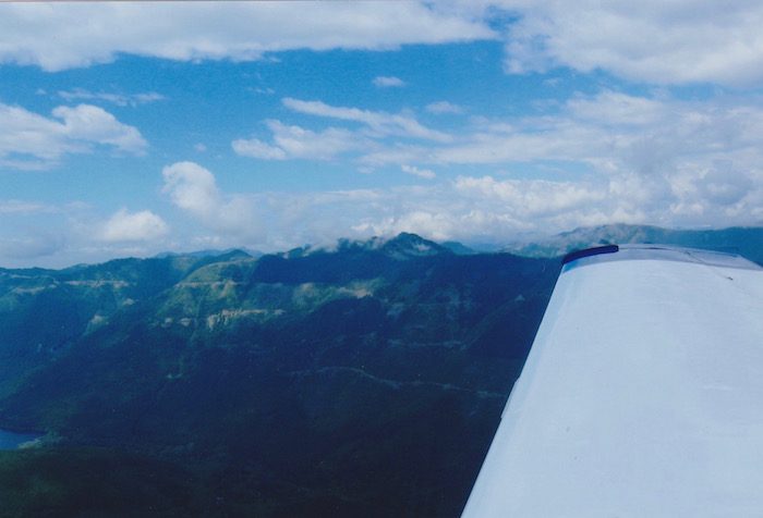 A view from the wing of an airplane with mountains in the background.